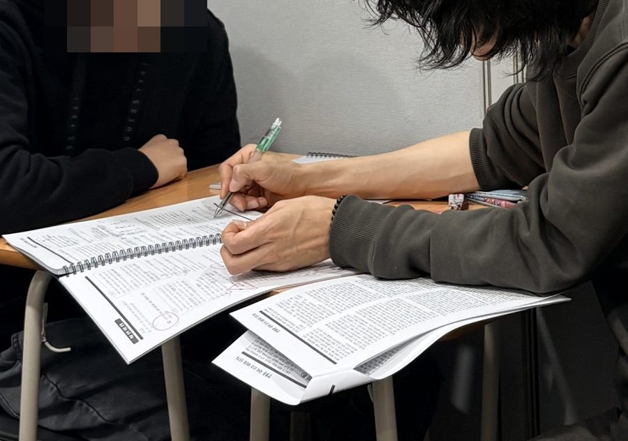 원장이 학생 교재에 펜으로 바로 표시하는 모습